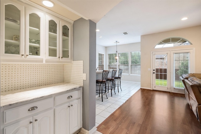 2713 Pasadena Pl, Flower Mound, TX 75022 - bar featuring light wood finished floors, backsplash, recessed lighting, hanging light fixtures, and baseboards
