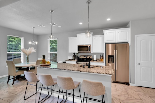 306 N Pendell Ave, Cleburne, TX 76033 - kitchen featuring appliances with stainless steel finishes, plenty of natural light, light stone counters, a center island with sink, and recessed lighting