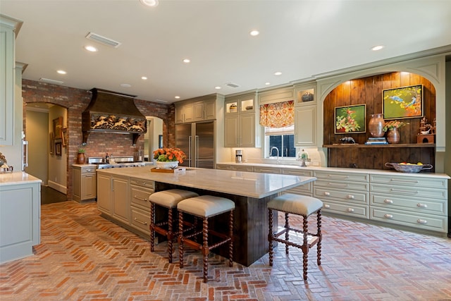303 Steeplechase Dr, Irving, TX 75062 - kitchen with built in refrigerator, premium range hood, brick floors, a breakfast bar area, and light countertops