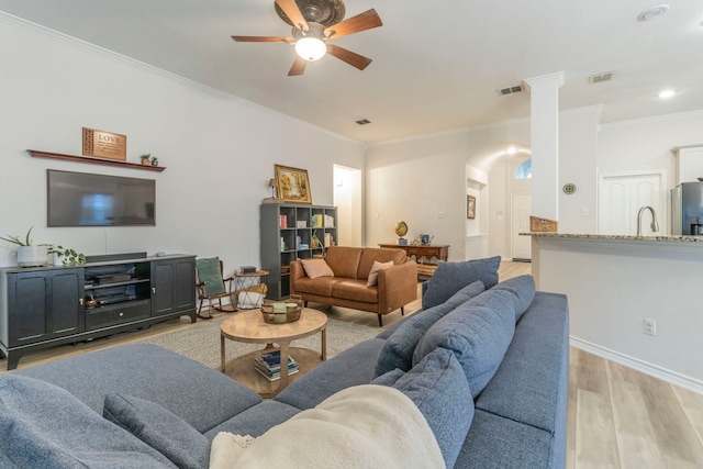 5428 Lake Powell Dr, Fort Worth, TX 76137 - living room featuring ceiling fan, light wood-style flooring, crown molding, arched walkways, and baseboards