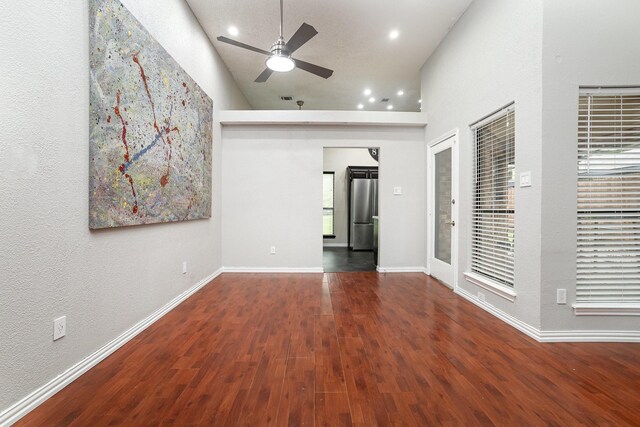 unfurnished living room featuring a ceiling fan, wooden walls, recessed lighting, a towering ceiling, and wood finished floors
