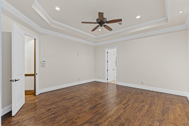 unfurnished room featuring a raised ceiling, ornamental molding, ceiling fan, dark wood finished floors, and baseboards