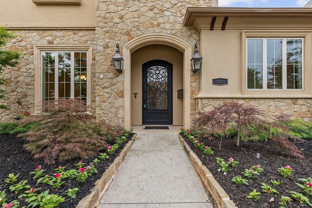 entrance to property with stone siding and stucco siding