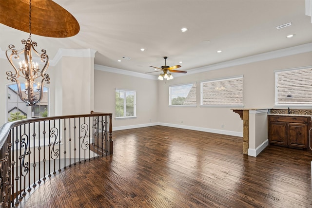 unfurnished living room featuring dark wood-style flooring, crown molding, ceiling fan, baseboards, and a chandelier
