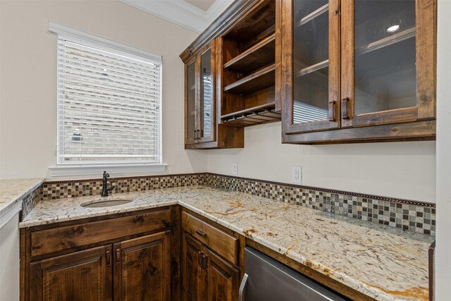 kitchen with a sink, crown molding, dark brown cabinets, glass insert cabinets, and light stone countertops