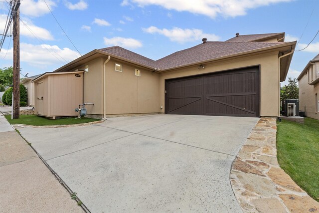 view of front of property featuring driveway, central AC, a garage, stucco siding, and a shingled roof