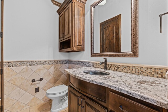bathroom featuring toilet, vanity, and tile walls