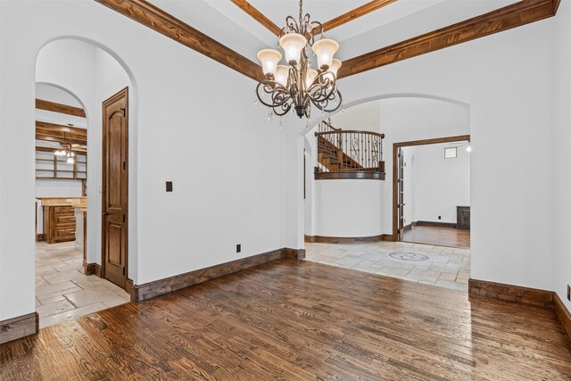 unfurnished dining area with arched walkways, stone tile flooring, baseboards, a chandelier, and stairway