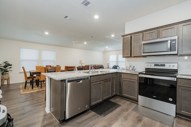 2308 Bellewood Ct, Crandall, TX 75114 - kitchen with stainless steel appliances, a sink, a peninsula, dark wood-style flooring, and tasteful backsplash