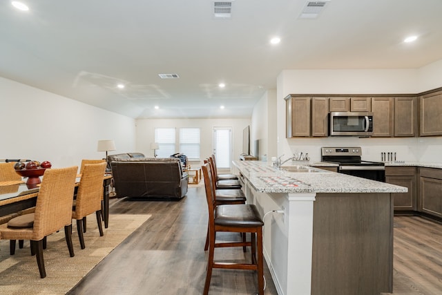 2308 Bellewood Ct, Crandall, TX 75114 - kitchen featuring appliances with stainless steel finishes, a sink, a breakfast bar area, dark wood-style floors, and open floor plan