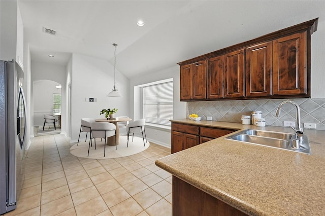 2691 Waterdance Dr, Little Elm, TX 75068 - kitchen with a sink, stainless steel refrigerator with ice dispenser, arched walkways, light tile patterned floors, and vaulted ceiling