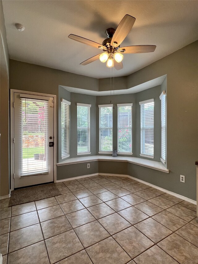 entryway featuring tile patterned floors, a ceiling fan, and baseboards