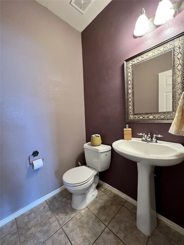 half bathroom with toilet, tile patterned floors, and baseboards