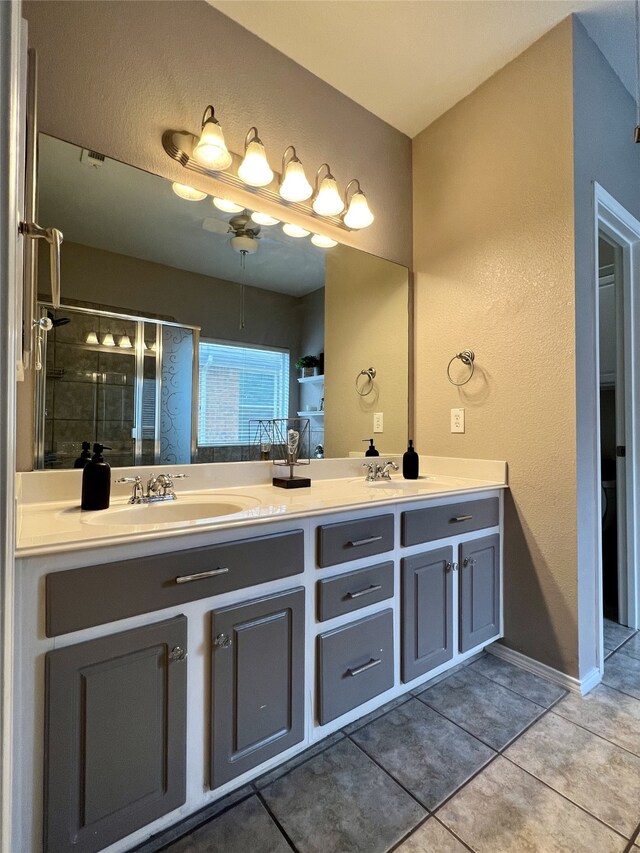 bathroom with double vanity, a shower stall, tile patterned floors, a textured wall, and ceiling fan