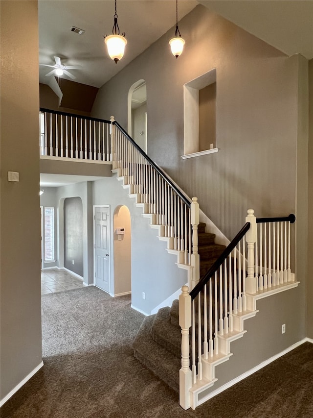 staircase featuring arched walkways, carpet flooring, a ceiling fan, and high vaulted ceiling
