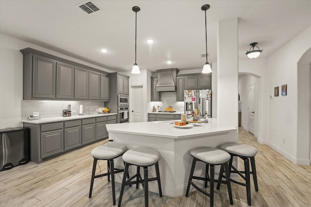 2643 Perdenales Dr, Royse City, TX 75189 - kitchen featuring stainless steel appliances, gray cabinets, arched walkways, custom range hood, and a breakfast bar area