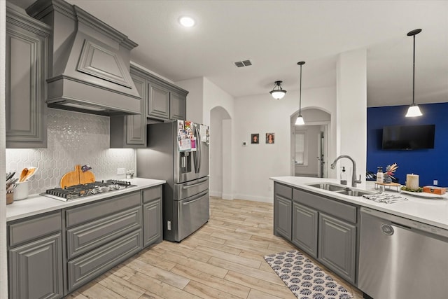 2643 Perdenales Dr, Royse City, TX 75189 - kitchen featuring arched walkways, stainless steel appliances, a sink, gray cabinetry, and custom exhaust hood