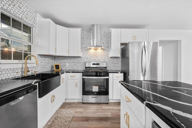 kitchen with appliances with stainless steel finishes, wall chimney exhaust hood, tasteful backsplash, and a sink
