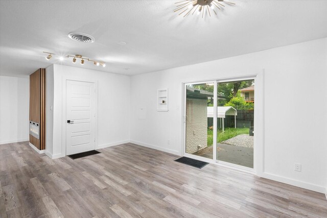 spare room with wood finished floors, baseboards, and track lighting