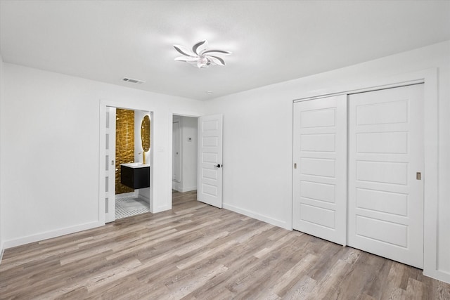 unfurnished bedroom featuring wood finished floors, a closet, and baseboards