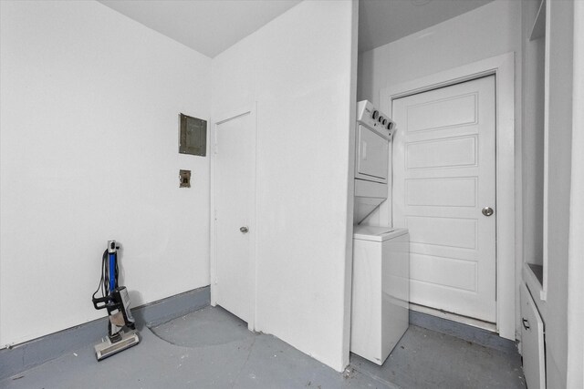 laundry area with stacked washing machine and dryer and electric panel