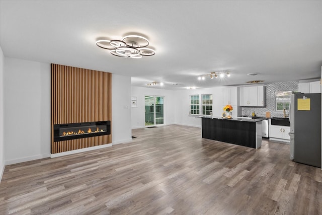 unfurnished living room with wood finished floors, a glass covered fireplace, and baseboards