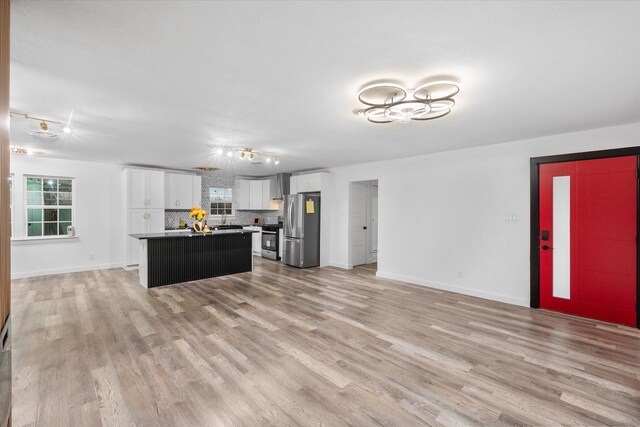 kitchen featuring stainless steel appliances, a center island, white cabinets, and light wood finished floors