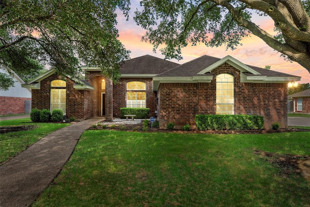 single story home with a front yard, brick siding, and roof with shingles