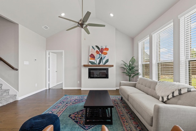 living area with wood finished floors, a ceiling fan, stairs, baseboards, and high vaulted ceiling