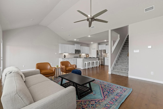 living area featuring baseboards, lofted ceiling, ceiling fan, stairs, and dark wood-style floors