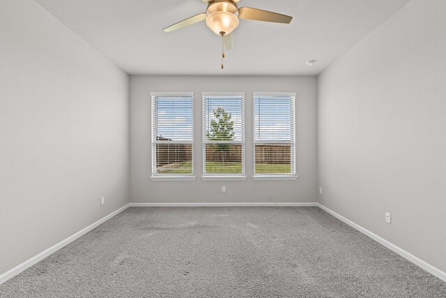 carpeted spare room featuring ceiling fan and baseboards