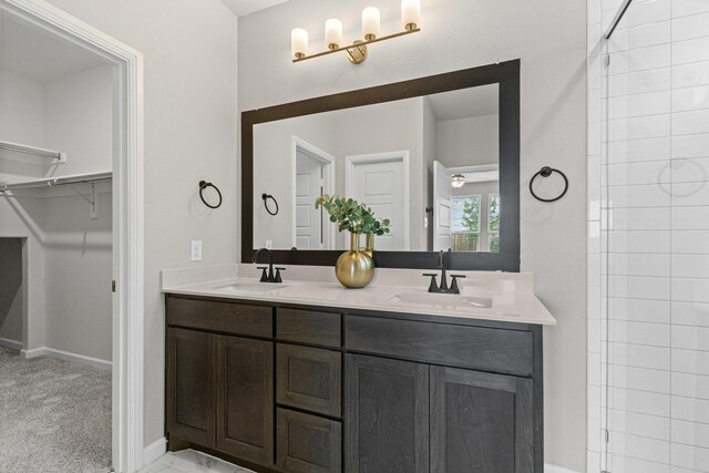 bathroom featuring double vanity, a spacious closet, and baseboards