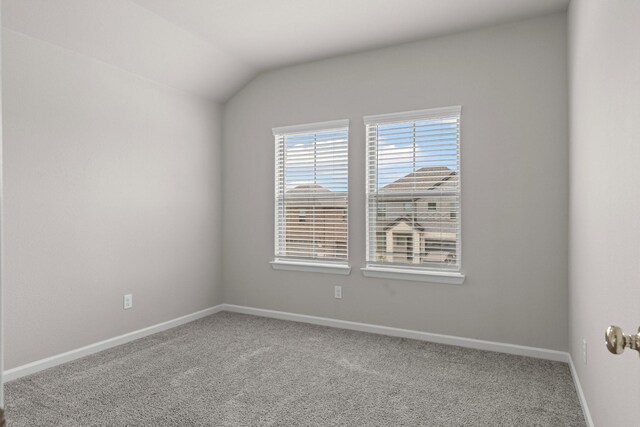 empty room featuring carpet, baseboards, and lofted ceiling