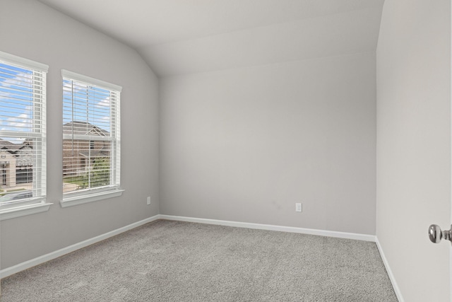 carpeted empty room with baseboards and vaulted ceiling