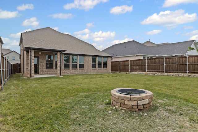 rear view of property with brick siding, an outdoor fire pit, roof with shingles, and a patio area