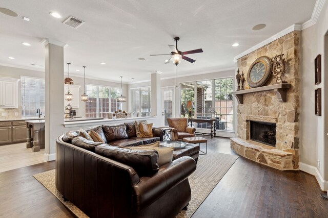 850 Long Valley Ct, Prosper, TX 75078 - living area featuring a ceiling fan, a stone fireplace, ornamental molding, healthy amount of natural light, and wood finished floors