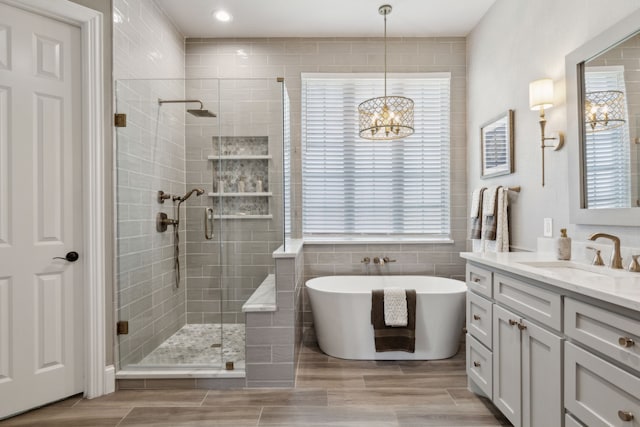 850 Long Valley Ct, Prosper, TX 75078 - bathroom with a shower stall, tile walls, vanity, a freestanding tub, and a chandelier