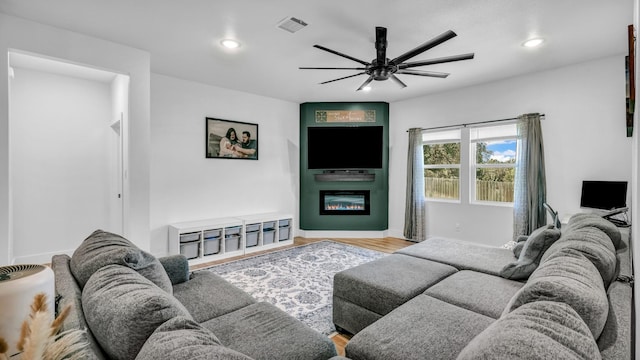 living area with a ceiling fan, a large fireplace, recessed lighting, wood finished floors, and baseboards
