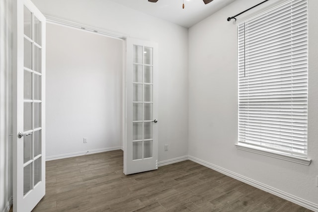 empty room with french doors, a ceiling fan, dark wood-type flooring, and baseboards