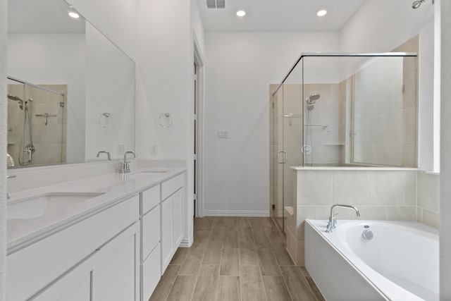 full bath featuring a stall shower, a garden tub, double vanity, and recessed lighting