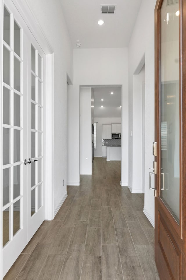 hallway featuring french doors, wood finished floors, baseboards, and recessed lighting