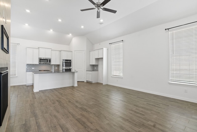 kitchen featuring stainless steel microwave, a ceiling fan, backsplash, open floor plan, and vaulted ceiling