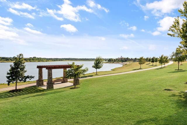 surrounding community with a water view and a yard