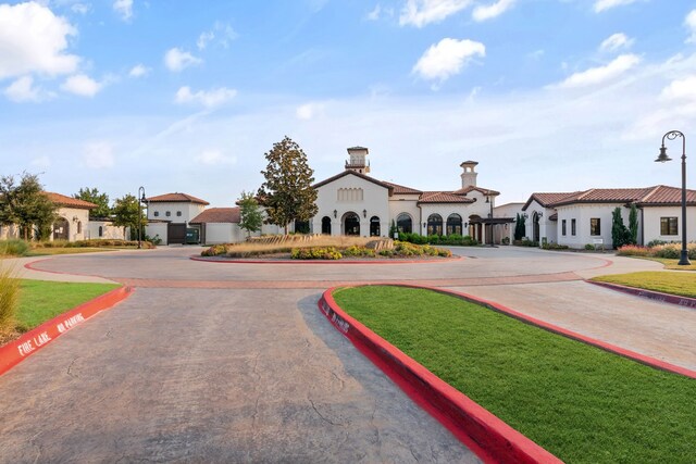 view of front of house with curved driveway, stucco siding, a front yard, and a residential view