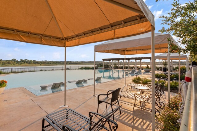 view of patio / terrace featuring a gazebo, a water view, an outdoor pool, and fence