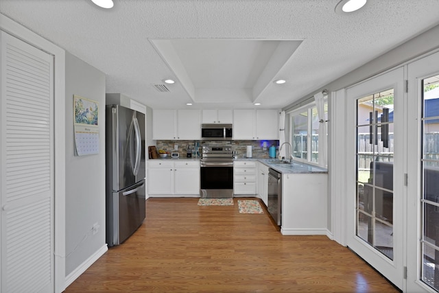 kitchen featuring appliances with stainless steel finishes, a sink, white cabinetry, tasteful backsplash, and recessed lighting