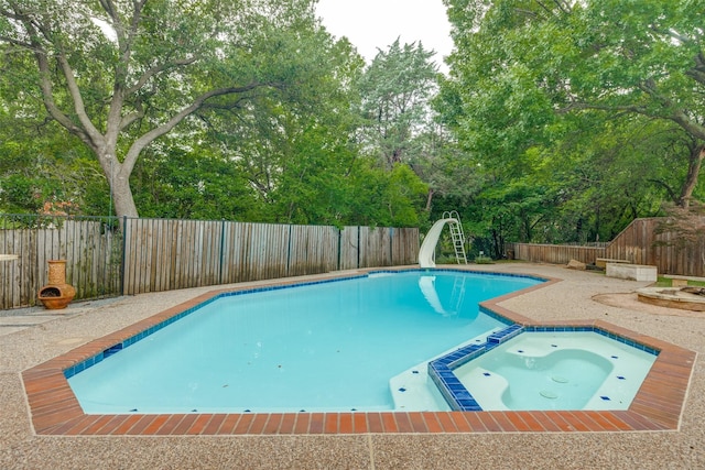 6701 Timothy Dr, Plano, TX 75023 - view of pool featuring a water slide, view of wooded area, a fenced backyard, and a pool with connected hot tub
