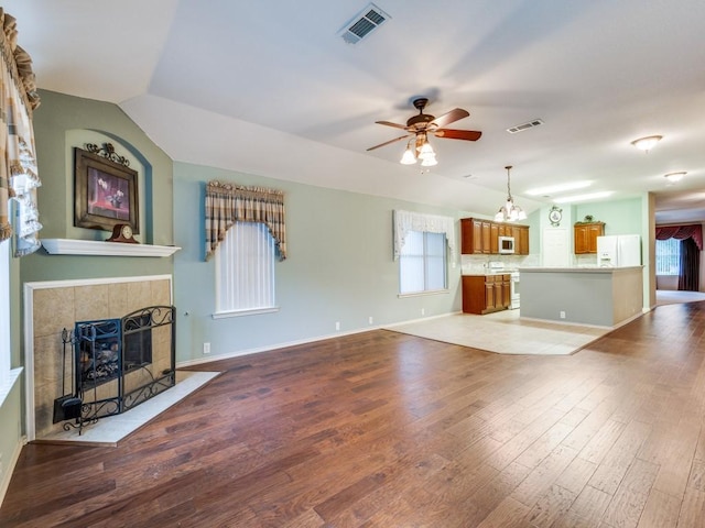 unfurnished living room with ceiling fan, a fireplace, a chandelier, wood finished floors, and baseboards