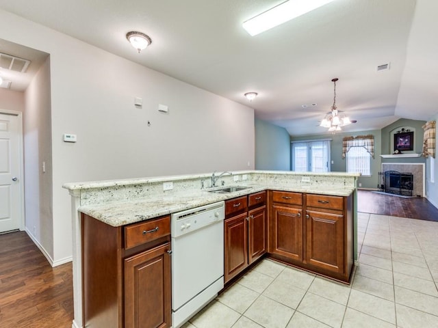 kitchen with dishwasher, a sink, open floor plan, a fireplace with raised hearth, and light stone countertops