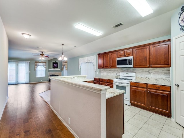 kitchen featuring white range with gas cooktop, ceiling fan, a fireplace, light stone countertops, and baseboards